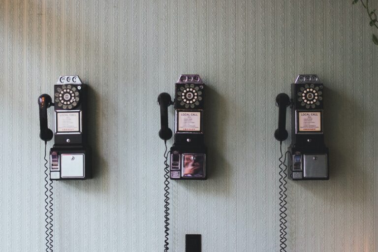 Three old dial telephones hanging from a wall