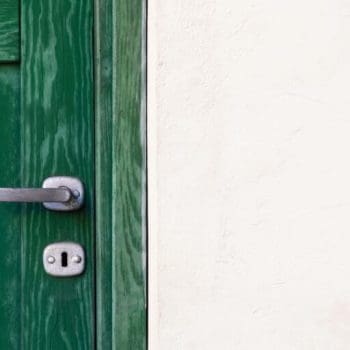 Close-up of a green door with a silver handle and keyhole