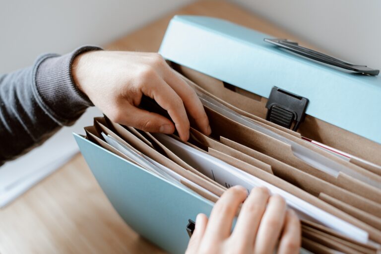 A person looking through a blue binder with various folders inside