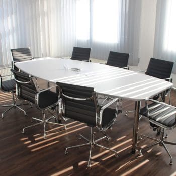 An empty board room meeting space with chairs beside a table