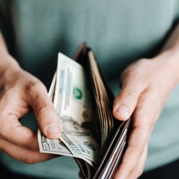 Close-up of a man pulling various bills from his wallet