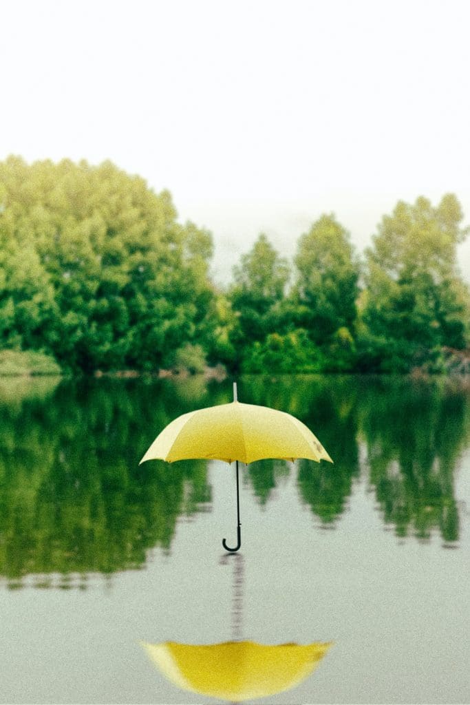 An open yellow umbrella sitting atop a body of water