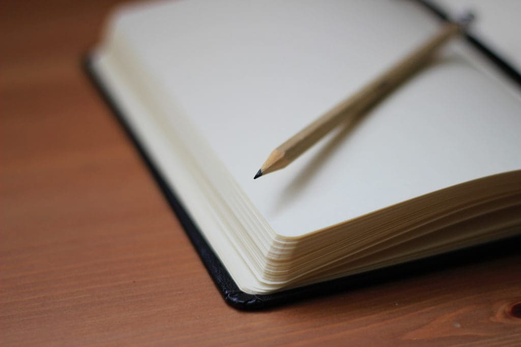 An open notebook with a pencil sitting on top