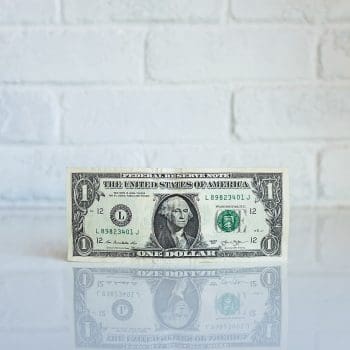 A $1 bill against a white tiled background