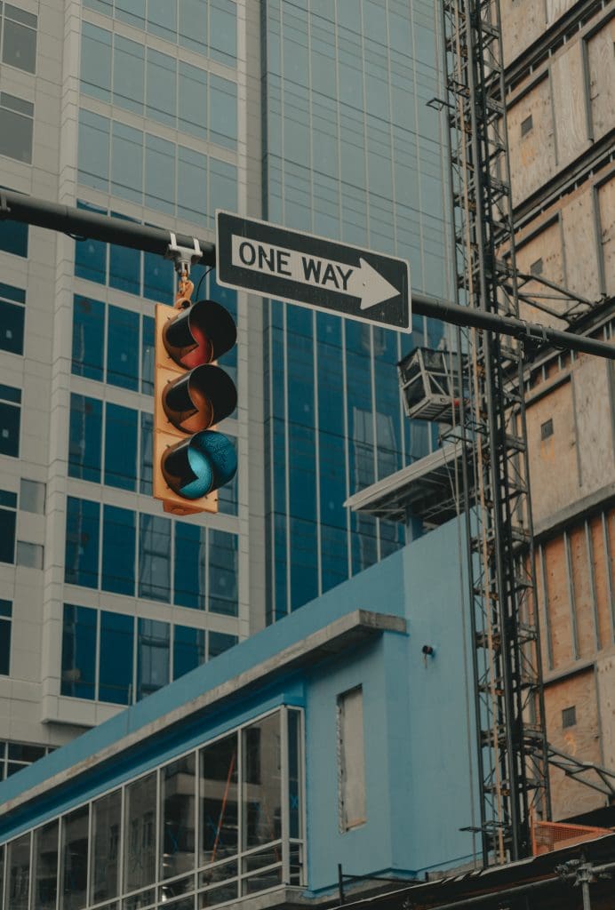 A street light with a green light and a "one way" sign pointing to the right