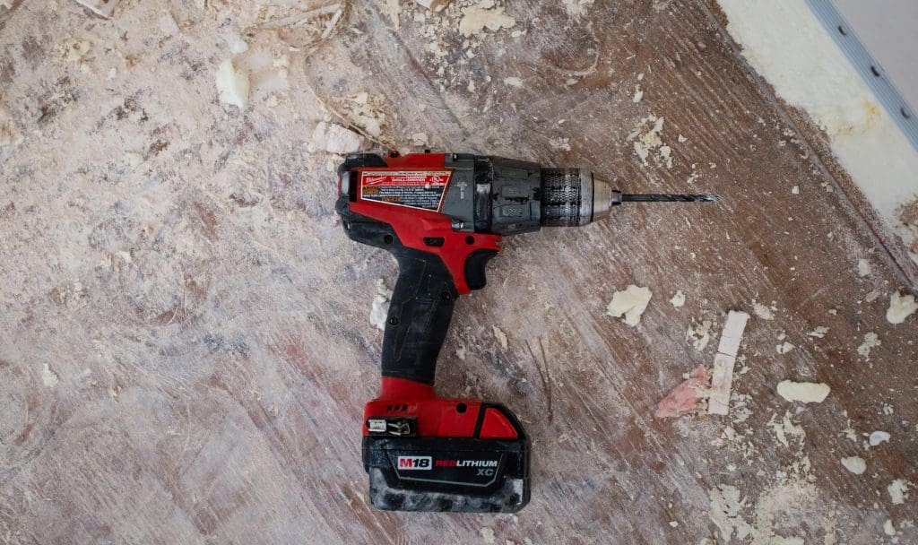 An electric power drill resting on a wooden floor