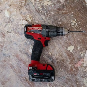 An electric power drill resting on a wooden floor