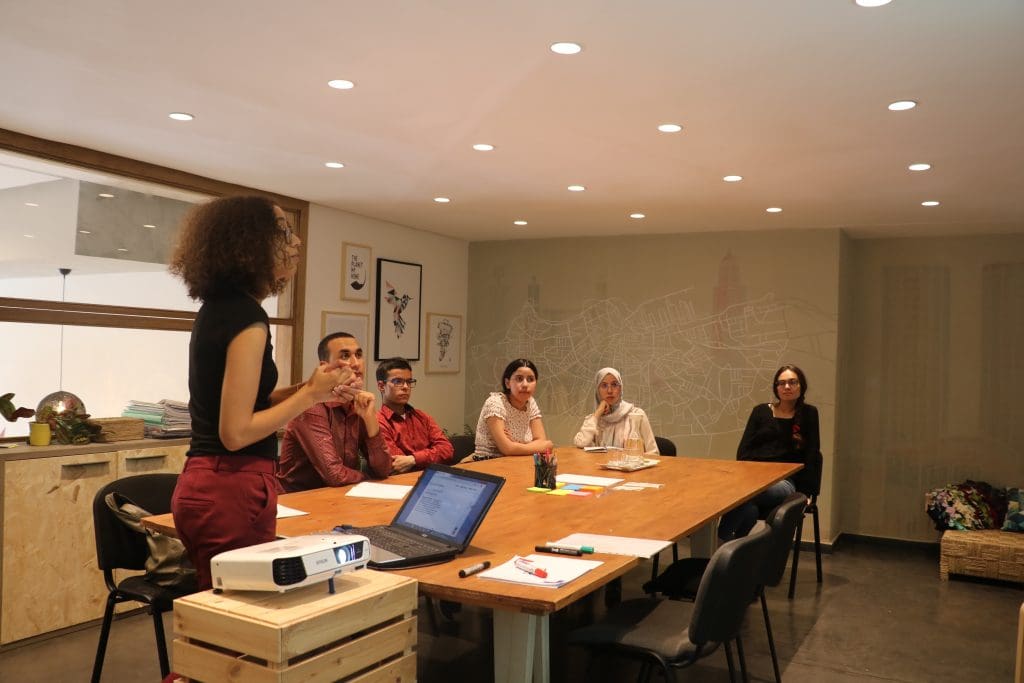 Six people sitting in a meeting room listening to a presentation