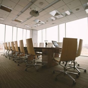 An empty workplace meeting room with chairs beside a long desk