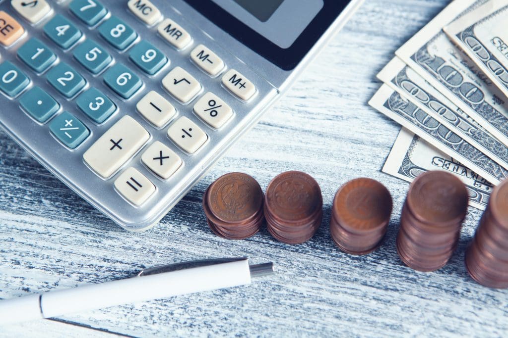 Pennies and $100 bills stacked next to a calculator